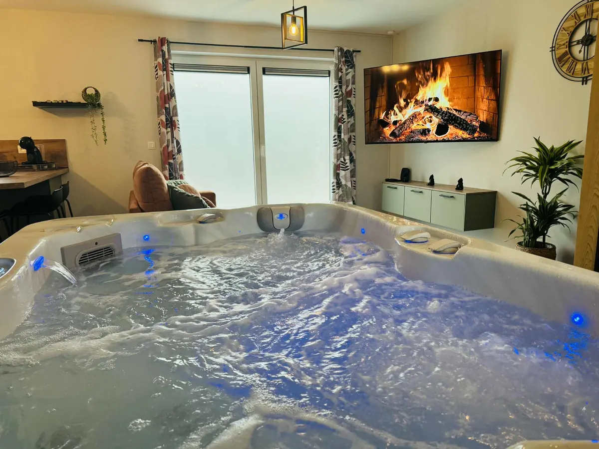 Jacuzzi privatif intérieur 4 places du gîte Le Cocon de Pernelle à Couvin, habillage en bois et ambiance tamisée